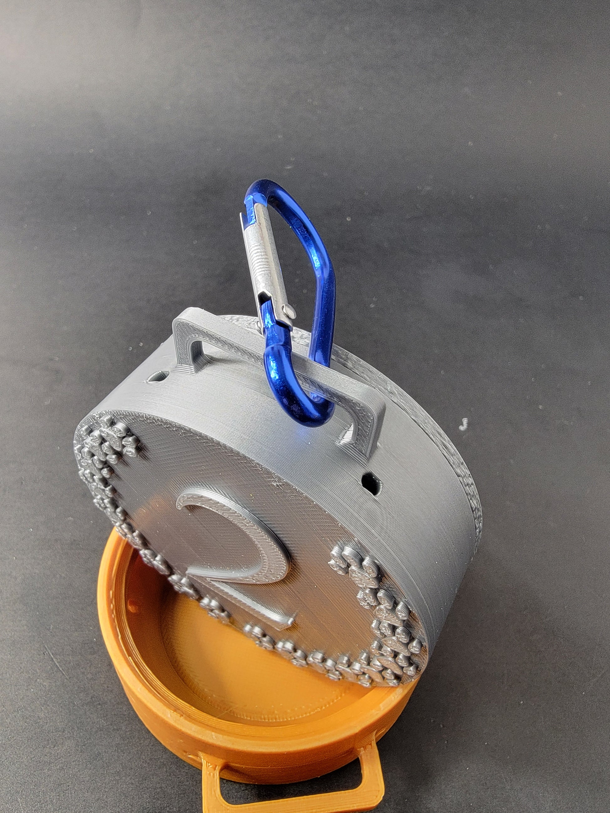Silver nose work medal hide attached to a blue carabiner, stacked on top of an open bronze medal hide base